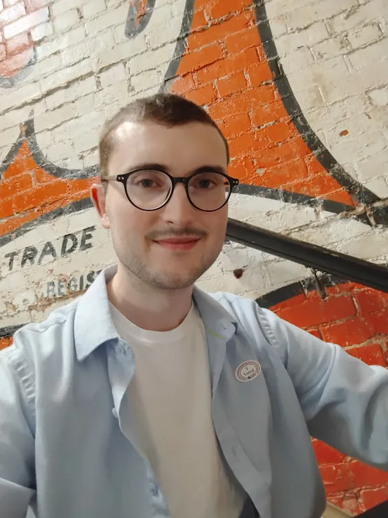 Jonathan near an old Coca-Cola brick wall.